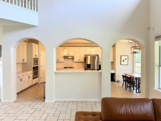 12504 Gun Metal Dr, Austin, TX 78739 - kitchen featuring stainless steel appliances, a towering ceiling, light countertops, under cabinet range hood, and decorative light fixtures