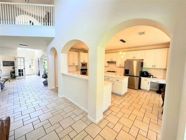 12504 Gun Metal Dr, Austin, TX 78739 - kitchen featuring appliances with stainless steel finishes, under cabinet range hood, light countertops, open floor plan, and a towering ceiling