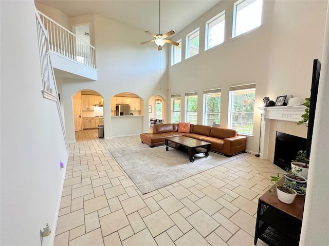 12504 Gun Metal Dr, Austin, TX 78739 - living area featuring a ceiling fan, a towering ceiling, a tile fireplace, and arched walkways