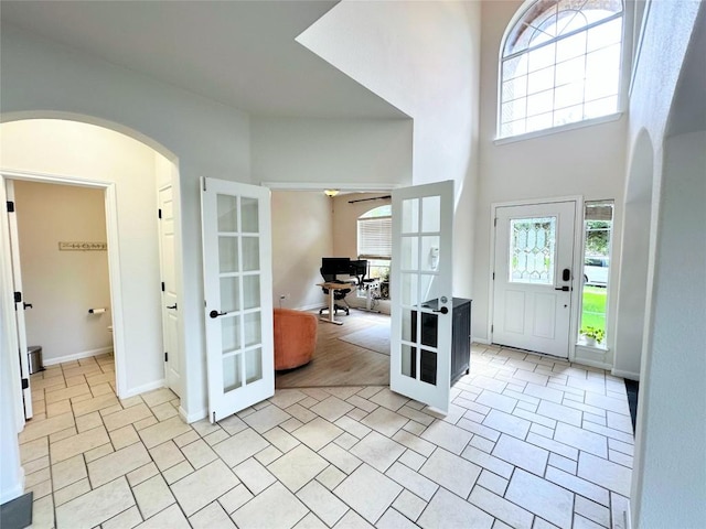 12504 Gun Metal Dr, Austin, TX 78739 - foyer with french doors, arched walkways, a ceiling fan, a high ceiling, and light tile patterned flooring