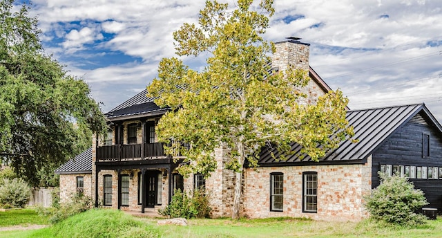 4204 Deer Tract St, Round Rock, TX 78681 - view of front facade with a standing seam roof, a metal roof, stone siding, a chimney, and a balcony