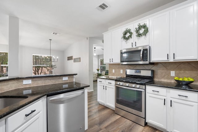 3713 Eagle Fledge Ter, Pflugerville, TX 78660 - kitchen with appliances with stainless steel finishes, light wood finished floors, decorative backsplash, white cabinets, and a chandelier