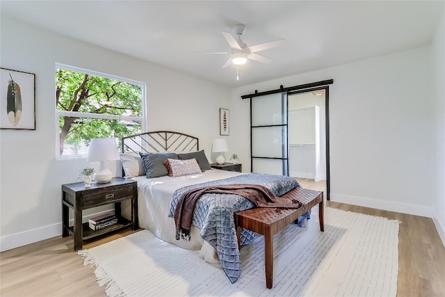 2402 Broken Oak Dr, Austin, TX 78745 - bedroom with a barn door, light wood-type flooring, and a ceiling fan