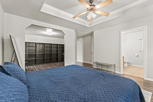 5302 Oster Dr, Killeen, TX 76542 - bedroom with crown molding, wood finished floors, a tray ceiling, a ceiling fan, and ensuite bathroom
