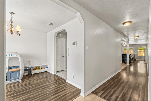 5302 Oster Dr, Killeen, TX 76542 - corridor featuring a textured ceiling, wood finished floors, and a chandelier