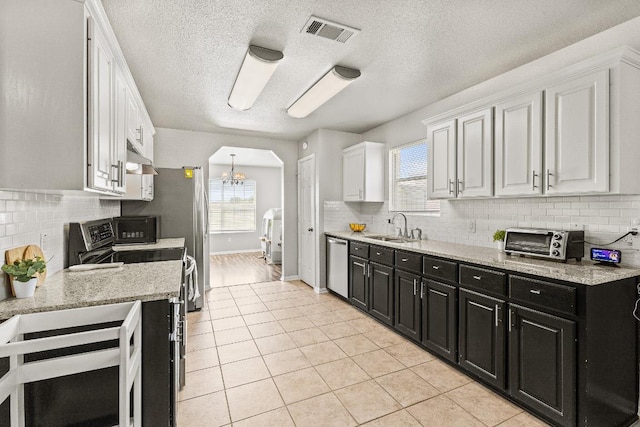 5302 Oster Dr, Killeen, TX 76542 - kitchen with dark cabinets, appliances with stainless steel finishes, white cabinets, arched walkways, and backsplash