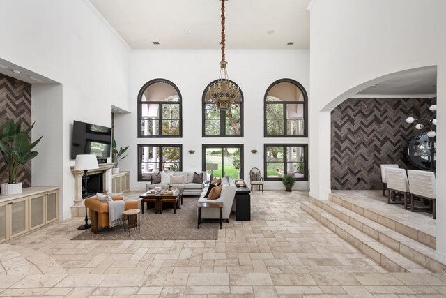 8634 Navidad Dr, Austin, TX 78735 - living area featuring a towering ceiling, ornamental molding, a fireplace, stone tile floors, and arched walkways