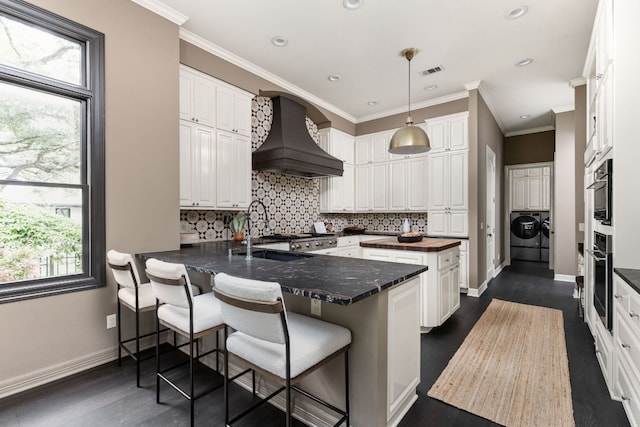 8634 Navidad Dr, Austin, TX 78735 - kitchen with custom range hood, washing machine and clothes dryer, stainless steel oven, white cabinets, and recessed lighting
