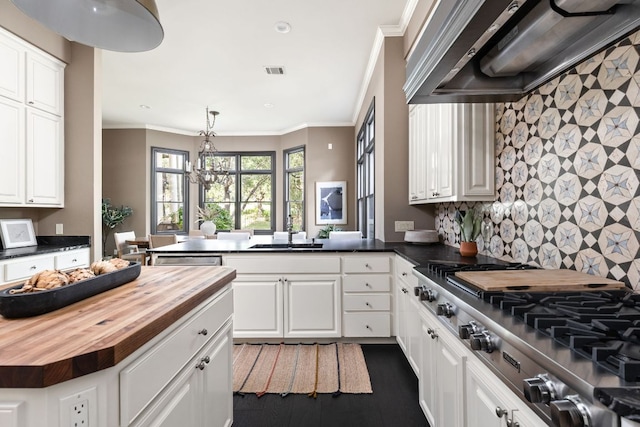 8634 Navidad Dr, Austin, TX 78735 - kitchen with butcher block counters, custom exhaust hood, stainless steel gas stovetop, white cabinets, and a peninsula