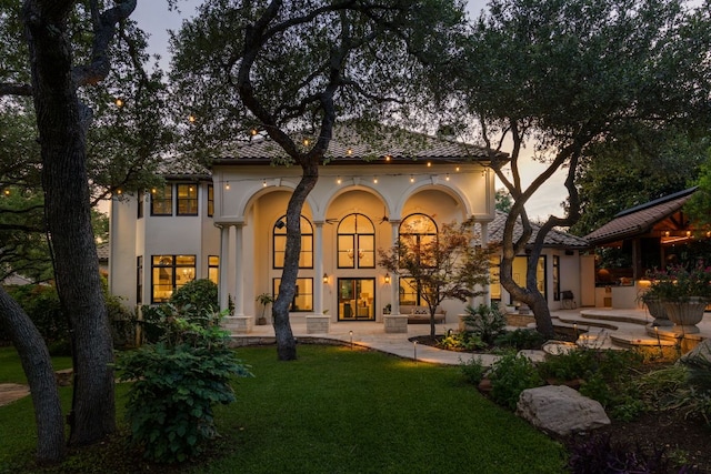 8634 Navidad Dr, Austin, TX 78735 - back of property at dusk featuring stucco siding and a lawn