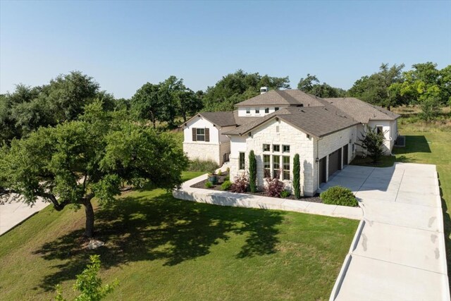 230 Wilderness Cv, Driftwood, TX 78619 - french country style house with concrete driveway, stone siding, a front yard, and an attached garage