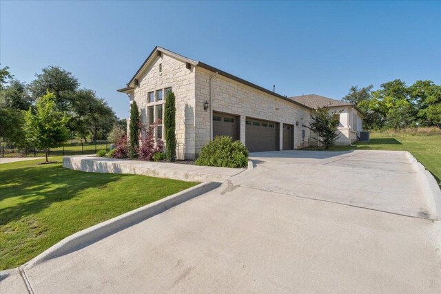 230 Wilderness Cv, Driftwood, TX 78619 - view of side of home with concrete driveway, stone siding, an attached garage, and a yard