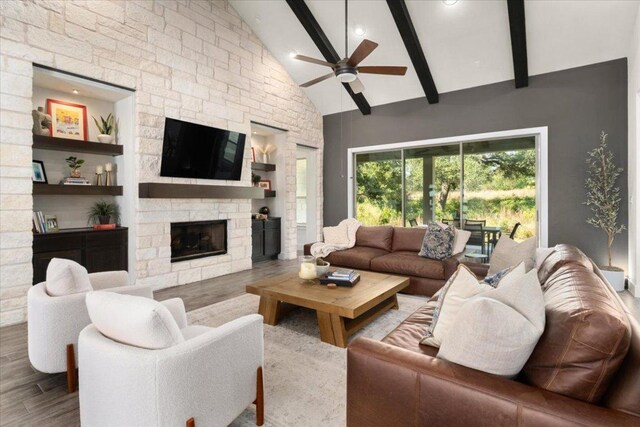 230 Wilderness Cv, Driftwood, TX 78619 - living room with ceiling fan, wood finished floors, beam ceiling, a stone fireplace, and high vaulted ceiling