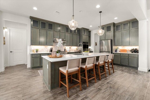 230 Wilderness Cv, Driftwood, TX 78619 - kitchen with stainless steel appliances, tasteful backsplash, light countertops, a breakfast bar area, and recessed lighting