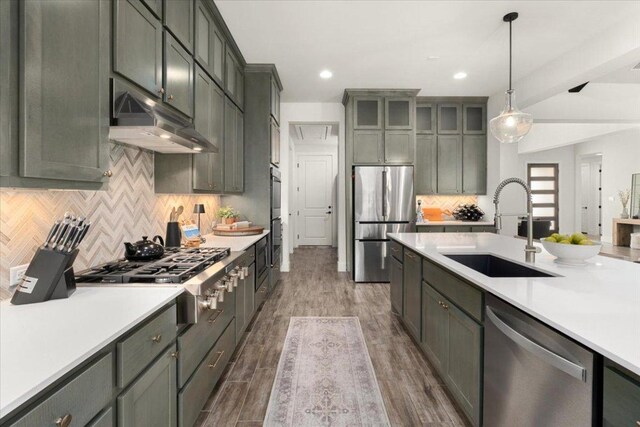 230 Wilderness Cv, Driftwood, TX 78619 - kitchen featuring stainless steel appliances, under cabinet range hood, light countertops, pendant lighting, and backsplash