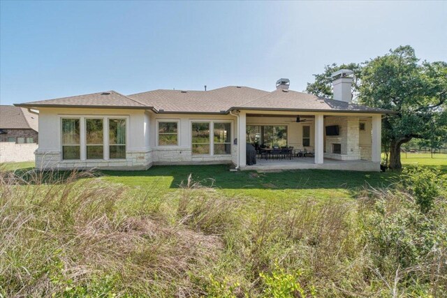 230 Wilderness Cv, Driftwood, TX 78619 - back of house with ceiling fan, a patio area, stone siding, a lawn, and a chimney