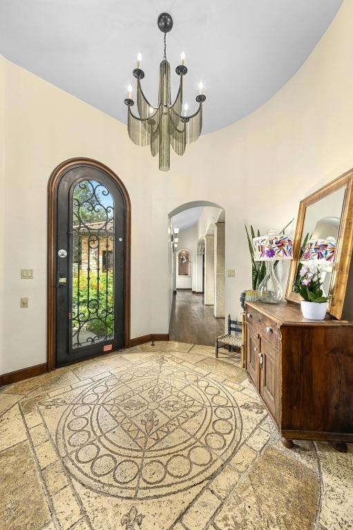 3816 Pappys Way, Austin, TX 78730 - entryway featuring inlaid floor details, arched walkways, a chandelier, a high ceiling, and stone tile flooring