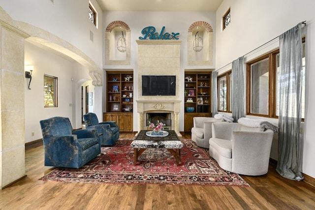3816 Pappys Way, Austin, TX 78730 - living room featuring a towering ceiling, wood finished floors, arched walkways, and a fireplace