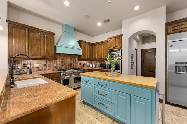3816 Pappys Way, Austin, TX 78730 - kitchen featuring premium appliances, arched walkways, custom range hood, butcher block counters, and a center island