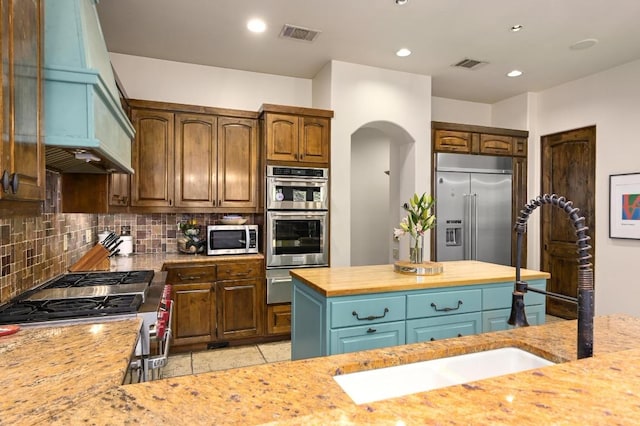 3816 Pappys Way, Austin, TX 78730 - kitchen featuring stainless steel appliances, custom range hood, decorative backsplash, arched walkways, and a warming drawer