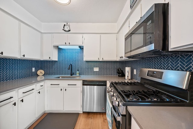 2801 Cornish Cir, Austin, TX 78745 - kitchen with stainless steel appliances, white cabinetry, and light wood finished floors