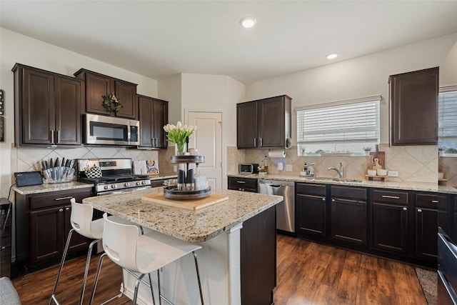 7304 Fall Ray Dr, Del Valle, TX 78617 - kitchen with appliances with stainless steel finishes, a center island, light stone counters, dark wood-type flooring, and decorative backsplash