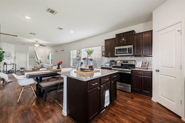 7304 Fall Ray Dr, Del Valle, TX 78617 - kitchen with stainless steel appliances, dark wood-style flooring, decorative backsplash, dark brown cabinets, and open floor plan