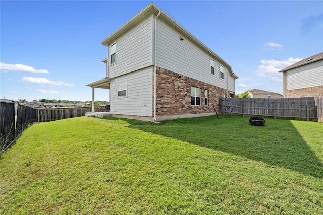 7304 Fall Ray Dr, Del Valle, TX 78617 - back of property featuring brick siding, a fenced backyard, and an outdoor fire pit