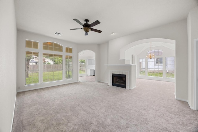 706 Cornell Dr, Pflugerville, TX 78660 - unfurnished living room featuring arched walkways, a tile fireplace, carpet flooring, a chandelier, and ceiling fan