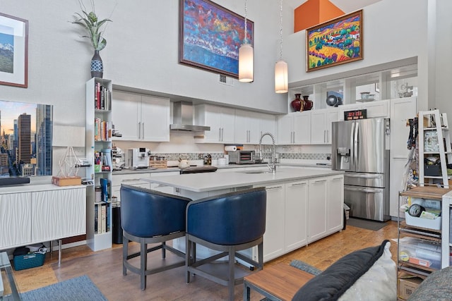 1600 Barton Springs Rd Unit 5406, Austin, TX 78704 - kitchen featuring stainless steel fridge, a high ceiling, wall chimney exhaust hood, light countertops, and light wood-style floors