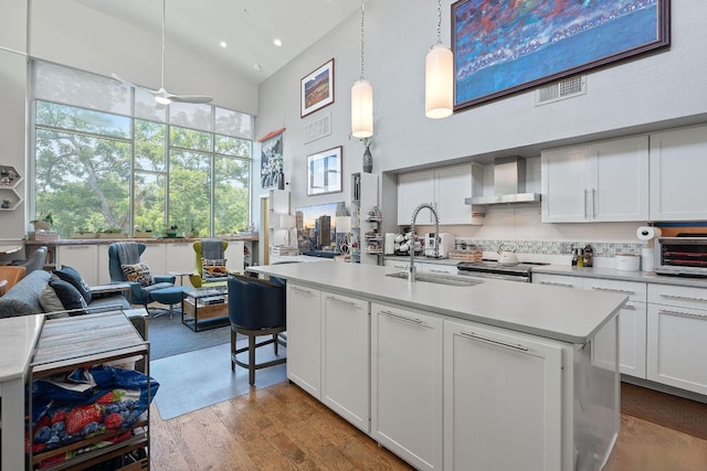 1600 Barton Springs Rd Unit 5406, Austin, TX 78704 - kitchen featuring wall chimney range hood, high vaulted ceiling, light countertops, white cabinetry, and wood finished floors