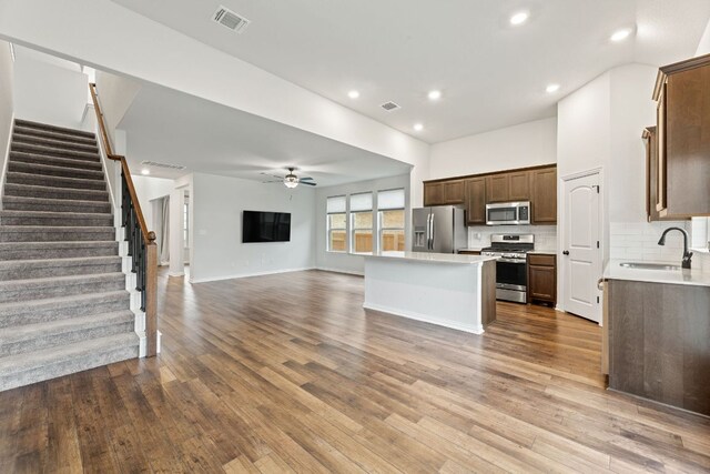 627 Cold River Run, Kyle, TX 78640 - kitchen with stainless steel appliances, open floor plan, a center island, a ceiling fan, and light countertops