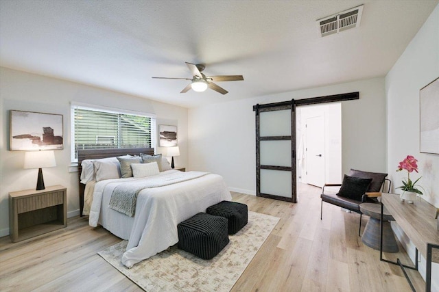 7906 Swindon Ln, Austin, TX 78745 - bedroom with a barn door, light wood-style flooring, and a ceiling fan