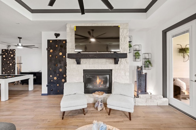 614 W Martingale St W, Georgetown, TX 78633 - living room featuring a ceiling fan, a tray ceiling, wood finished floors, ornamental molding, and a stone fireplace