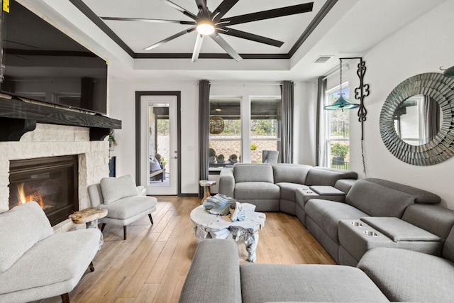 614 W Martingale St W, Georgetown, TX 78633 - living area featuring a tray ceiling, ceiling fan, hardwood / wood-style flooring, ornamental molding, and a stone fireplace