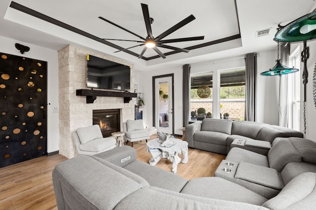 614 W Martingale St W, Georgetown, TX 78633 - living area with a ceiling fan, a raised ceiling, wood finished floors, and a stone fireplace