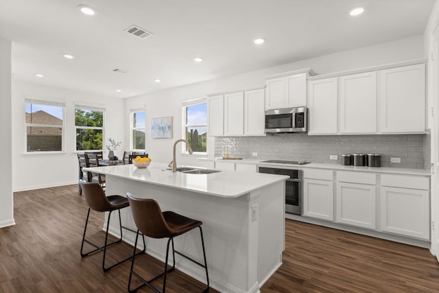 2004 Long Shadow Ln, Georgetown, TX 78628 - kitchen featuring appliances with stainless steel finishes, an island with sink, tasteful backsplash, a breakfast bar area, and dark wood-style flooring