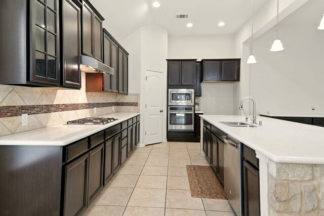 2516 Silver Fern Ln, Pflugerville, TX 78660 - kitchen featuring stainless steel appliances, under cabinet range hood, tasteful backsplash, glass insert cabinets, and pendant lighting