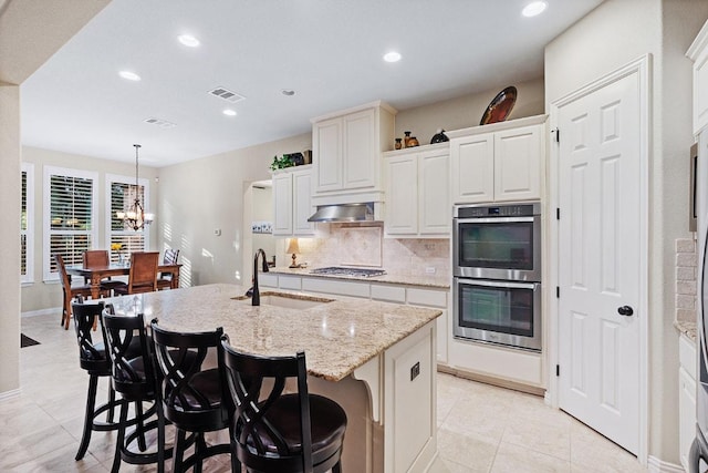 128 Lady Bird Ln, Georgetown, TX 78628 - kitchen featuring stainless steel appliances, decorative backsplash, recessed lighting, light tile patterned floors, and an island with sink