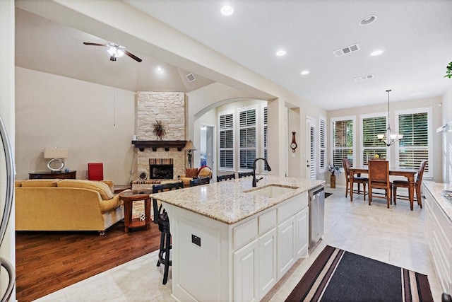 128 Lady Bird Ln, Georgetown, TX 78628 - kitchen featuring stainless steel dishwasher, a fireplace, ceiling fan, white cabinetry, and light stone countertops