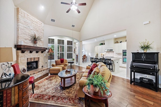 128 Lady Bird Ln, Georgetown, TX 78628 - living room with ceiling fan, light wood-style floors, high vaulted ceiling, a fireplace, and arched walkways