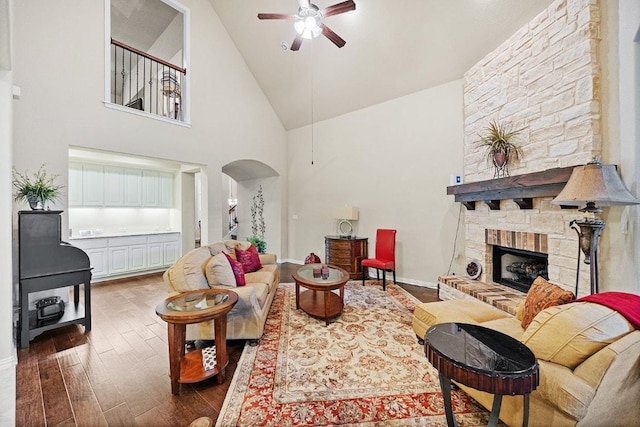 128 Lady Bird Ln, Georgetown, TX 78628 - living room with ceiling fan, dark wood finished floors, arched walkways, a stone fireplace, and high vaulted ceiling