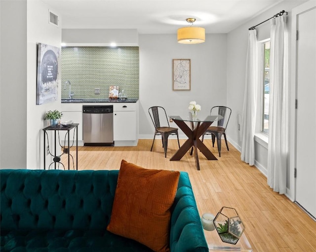 living area with light wood-type flooring and bar