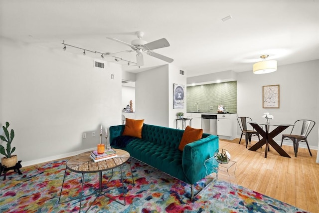 living room with a ceiling fan, light wood-style flooring, and track lighting