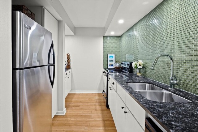 kitchen featuring stainless steel appliances, white cabinetry, light wood finished floors, dark stone counters, and recessed lighting