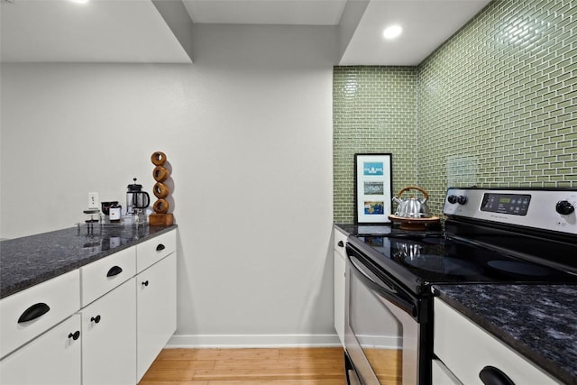 kitchen featuring stainless steel electric range, light wood-style floors, white cabinetry, dark stone countertops, and recessed lighting