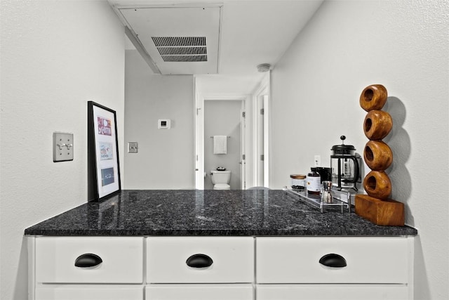 kitchen with white cabinetry and dark stone counters
