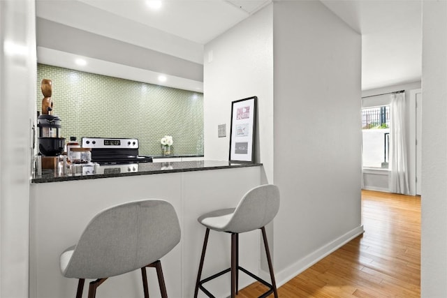 bar area with stainless steel range with electric cooktop, wood finished floors, and recessed lighting