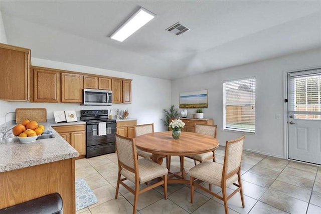 12701 Paloma Blanca Way, Del Valle, TX 78617 - kitchen featuring black electric range oven, stainless steel microwave, light countertops, brown cabinets, and light tile patterned flooring