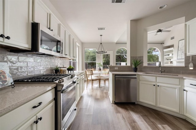 4604 Hibiscus Valley Dr, Austin, TX 78739 - kitchen featuring stainless steel appliances, backsplash, wood finished floors, a ceiling fan, and hanging light fixtures